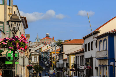 Houses by street in city against sky