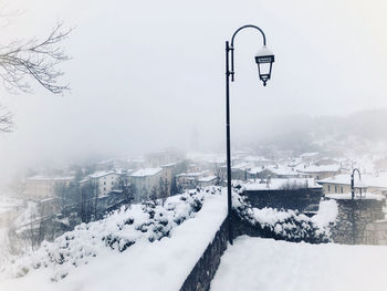 Snow covered street against sky during winter