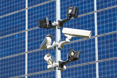 Low angle view of security cameras against solar panels