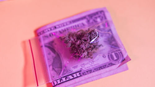 High angle view of marijuana on paper currency over table