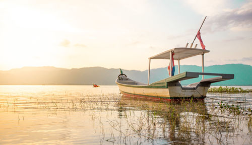 Beauiful sunset scenery of a boat by the lakeside of timah tasoh lake and hills as the background 