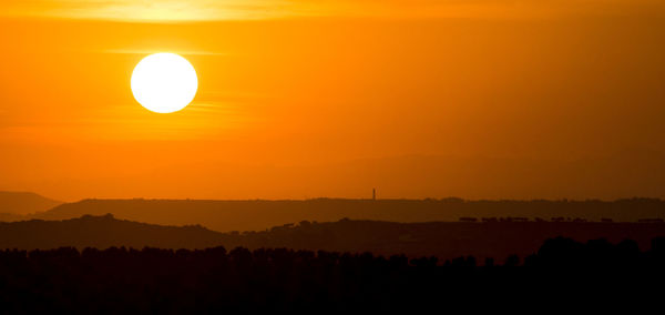 Scenic view of silhouette landscape against orange sky