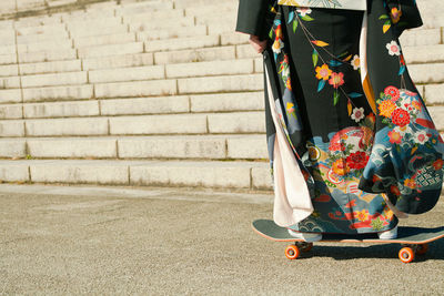 Low section of woman skateboarding in traditional clothing