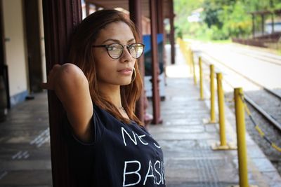 Portrait of young woman standing at railroad station