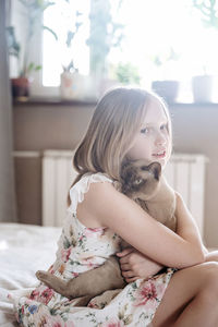 Portrait of young woman sitting on bed at home