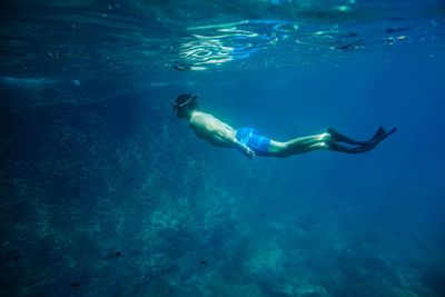 Shirtless young man scuba diving in sea