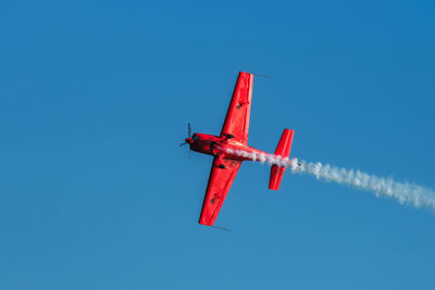 Low angle view of airplane flying against clear blue sky