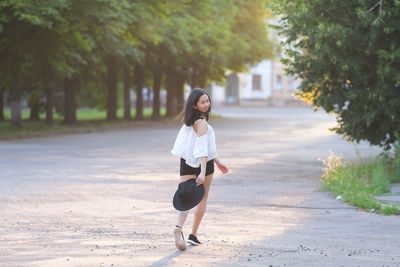Full length portrait of young woman on footpath