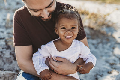 Close up of father holding young toddler girl at beach