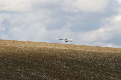 Low angle view of airplane over field against sky