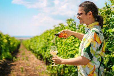 Man pouring wine in glass in vineyard