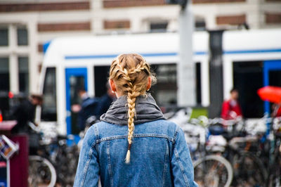 Rear view of young woman with braided hair standing in city
