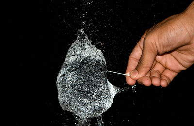 Close-up of man holding hands over black background