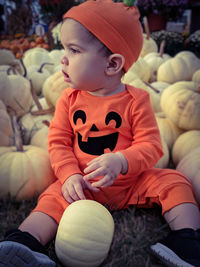 Cute boy with pumpkins sitting during halloween