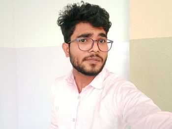 Portrait of young man standing against wall