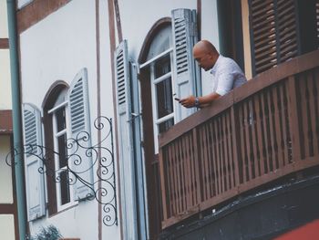 Side view of young man standing on staircase against building