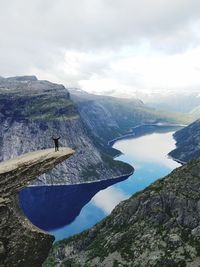 Man on cliff against river and mountains