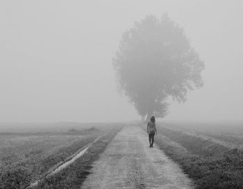 Man walking on agricultural field against clear sky