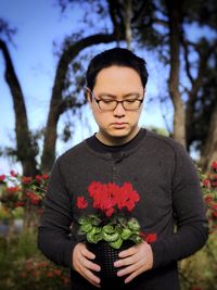 Low section of woman standing on red flowering plant