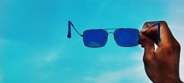 Low section of person wearing sunglasses against swimming pool