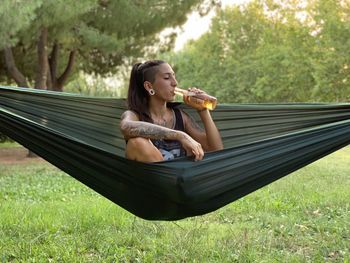 Young woman sitting on hammock in field