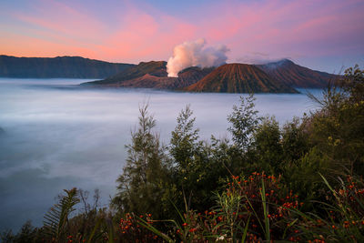 Smoke emitting from volcanic mountain against sky during sunset