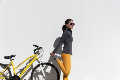 Woman cyclist standing doing a leg stretch