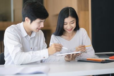 Young couple looking at camera while sitting on table