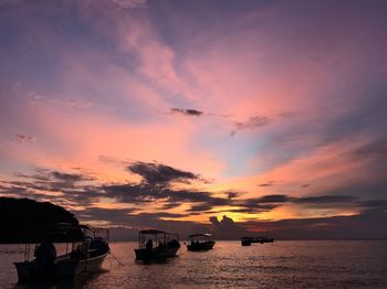 Silhouette boats in sea against sky during sunset