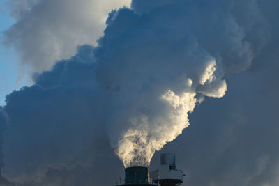 Smoke stacks pour pollution backlit by sunrise