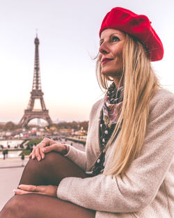 Beautiful young woman wearing hat against tower in city