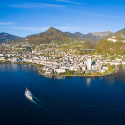 Aerial view of buildings by sea against blue sky