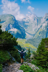 Rear view of man standing on mountain against sky