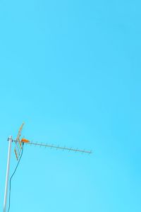 Low angle view of birds perching on cable against clear blue sky