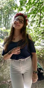 Portrait of beautiful young woman standing against plants