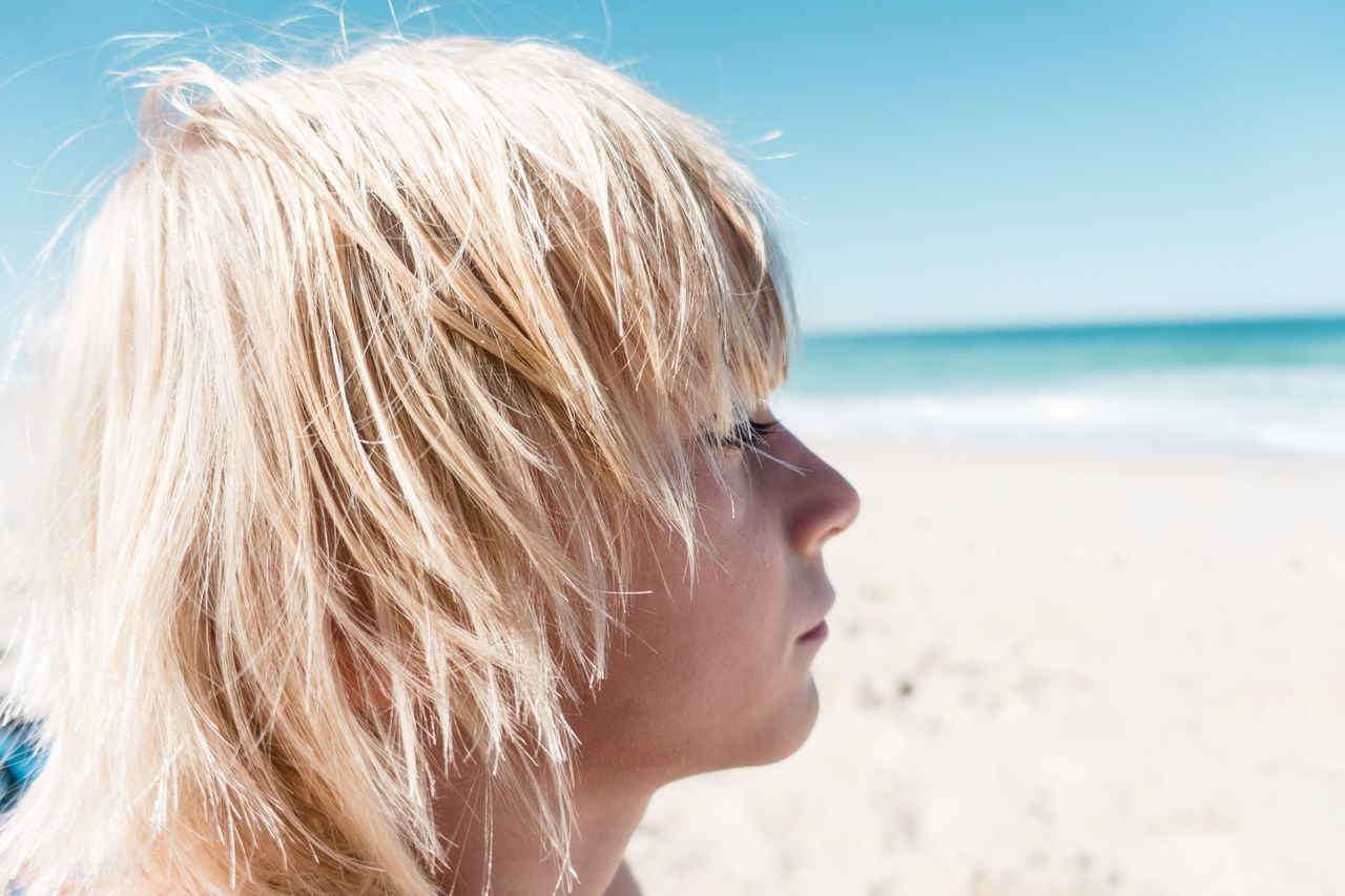 CLOSE-UP PORTRAIT OF MID ADULT WOMAN ON BEACH