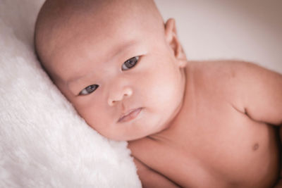 Portrait of cute baby girl lying on bed