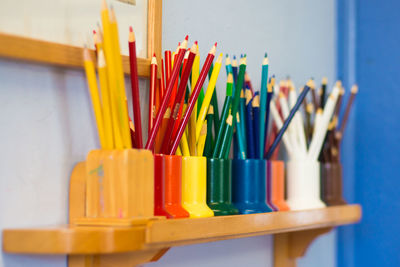 Colorful pencils in desk organizers on shelf
