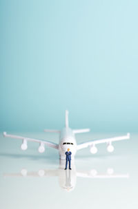 Airplane model and pilot figurine on table against blue background