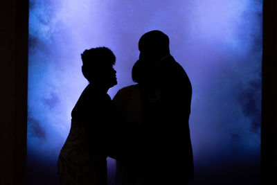 Silhouette couple standing against blue sky