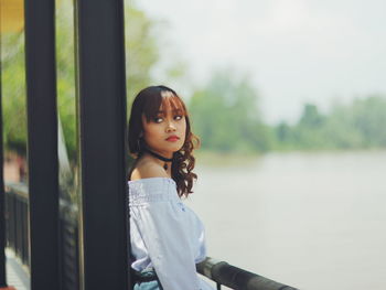 Young woman leaning on railing by lake