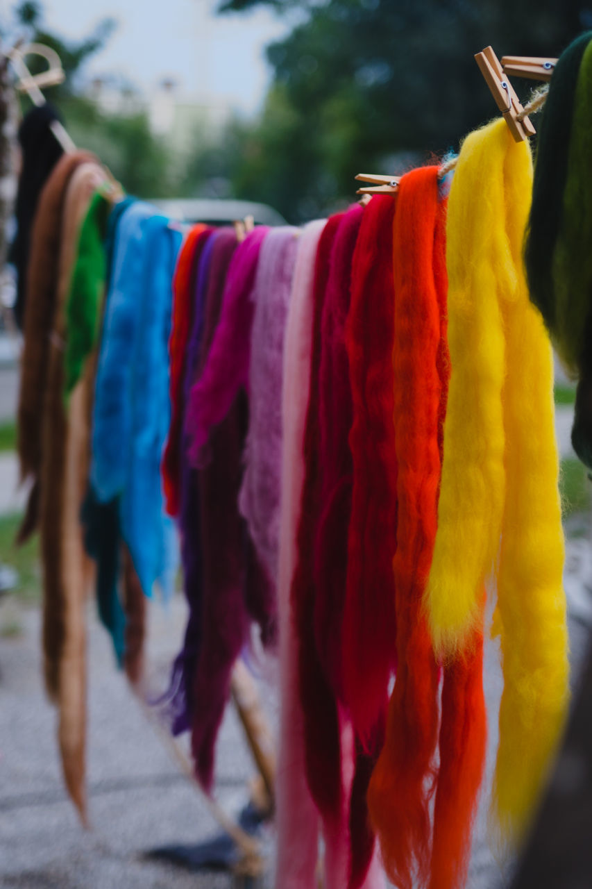 CLOSE-UP OF MULTI COLORED CLOTHES HANGING ON MARKET