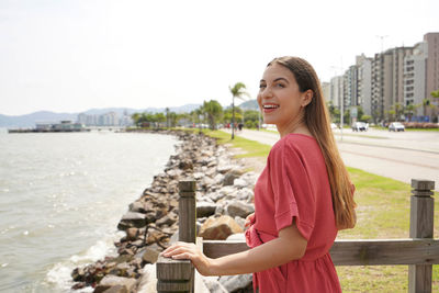 Portrait of smiling fashion woman enjoying relaxed on seafront of florianopolis, brazil