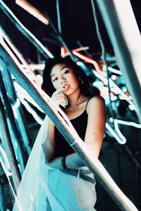 Portrait of beautiful young woman standing against railing