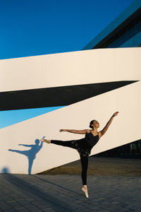 Young woman practicing ballet dance against structure