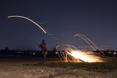 Rear view of man standing on field at night
