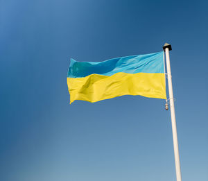 Low angle view of flag against clear blue sky