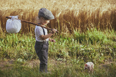 The little traveler met a piglet in the field. retro photo.