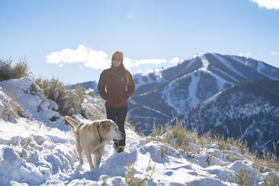 A woman walking with her dogs on a cold winter day.