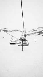 Ski lift on snow covered shore against clear sky